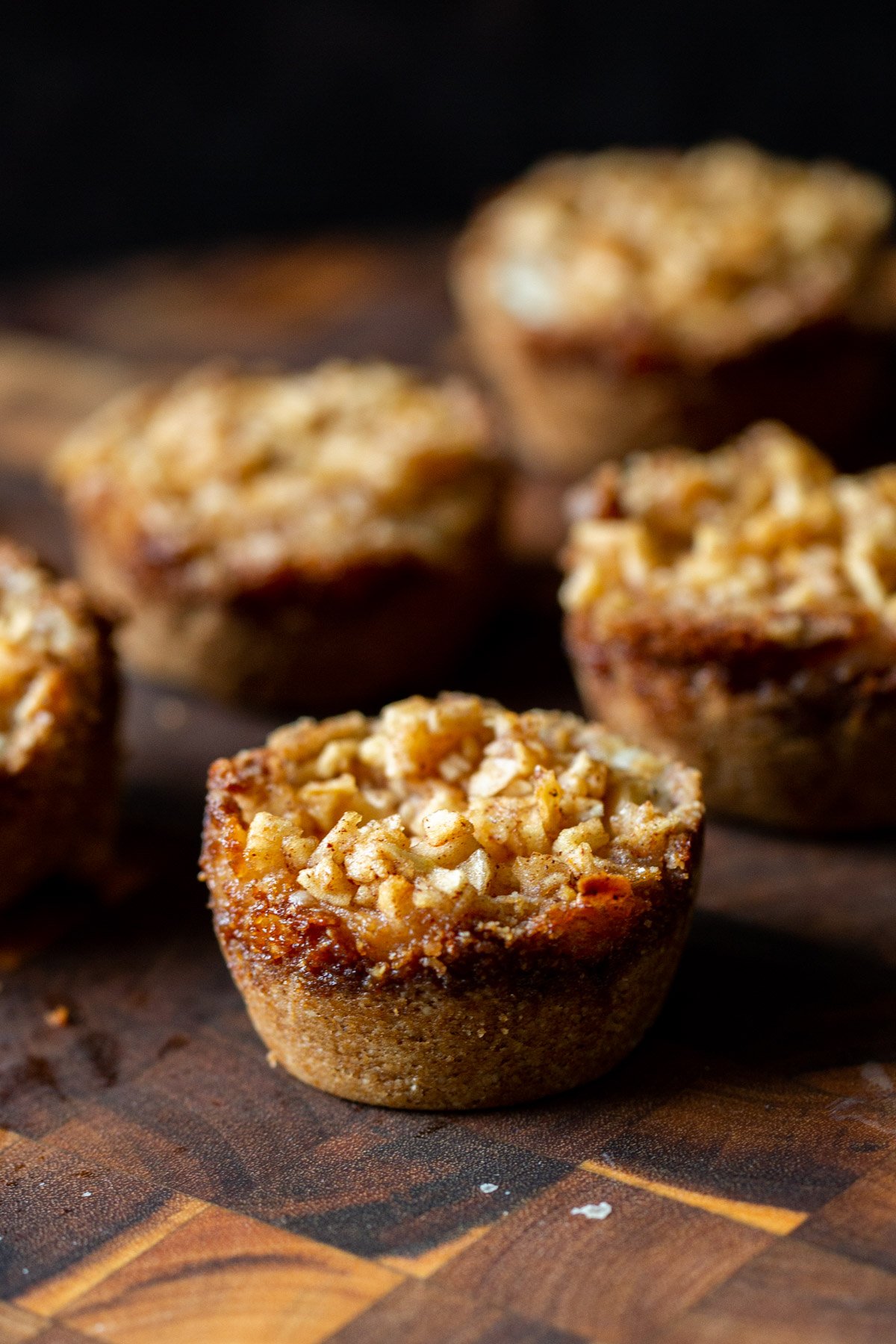 side view of vegan mini apple pie cheesecakes on a wooden board