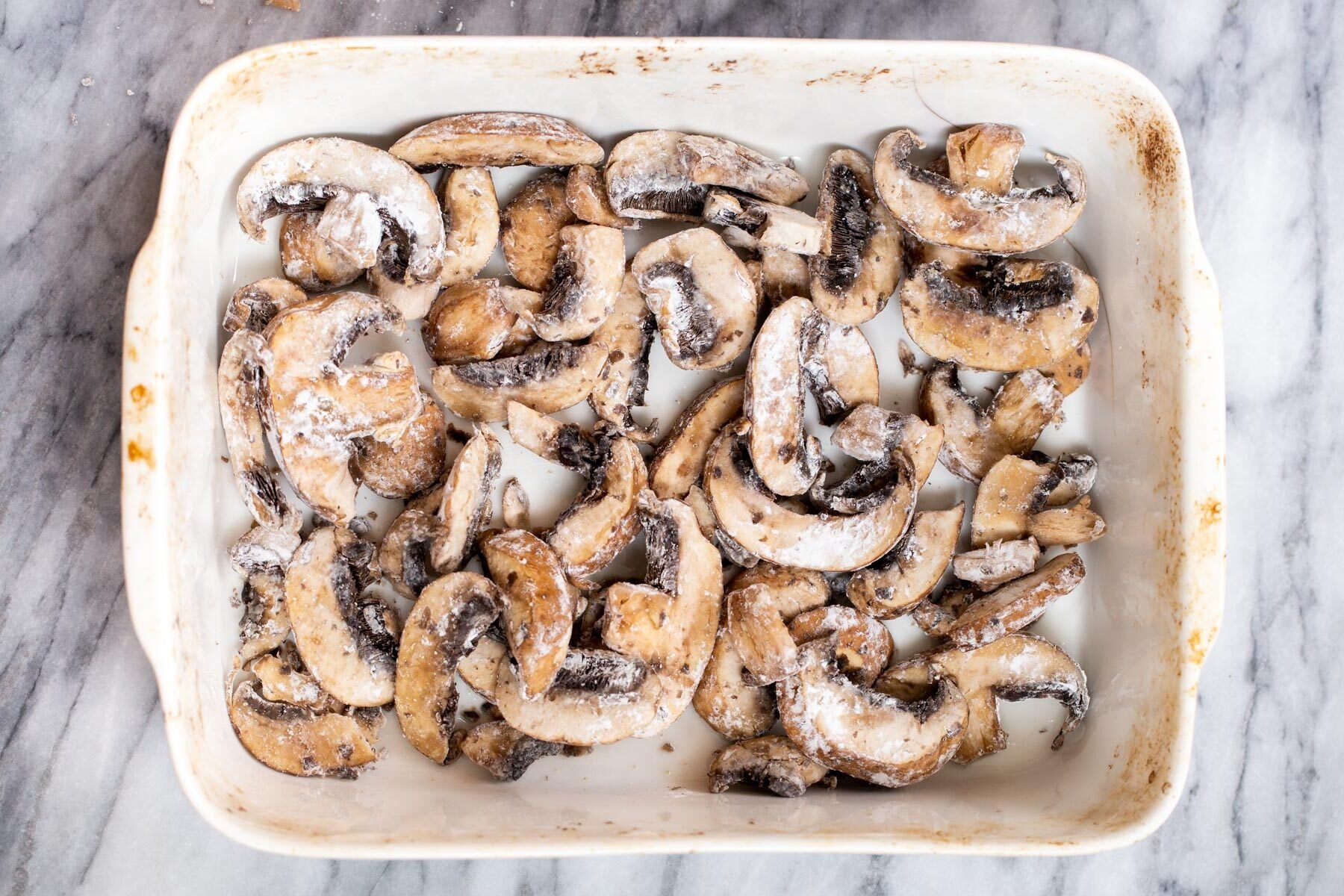 cornstarch coated mushroom slices in a casserole dish