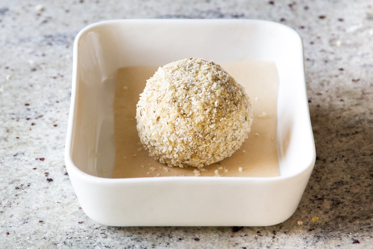 vegan stuffing cheeseball in a small white casserole dish ready for being heated in the oven 