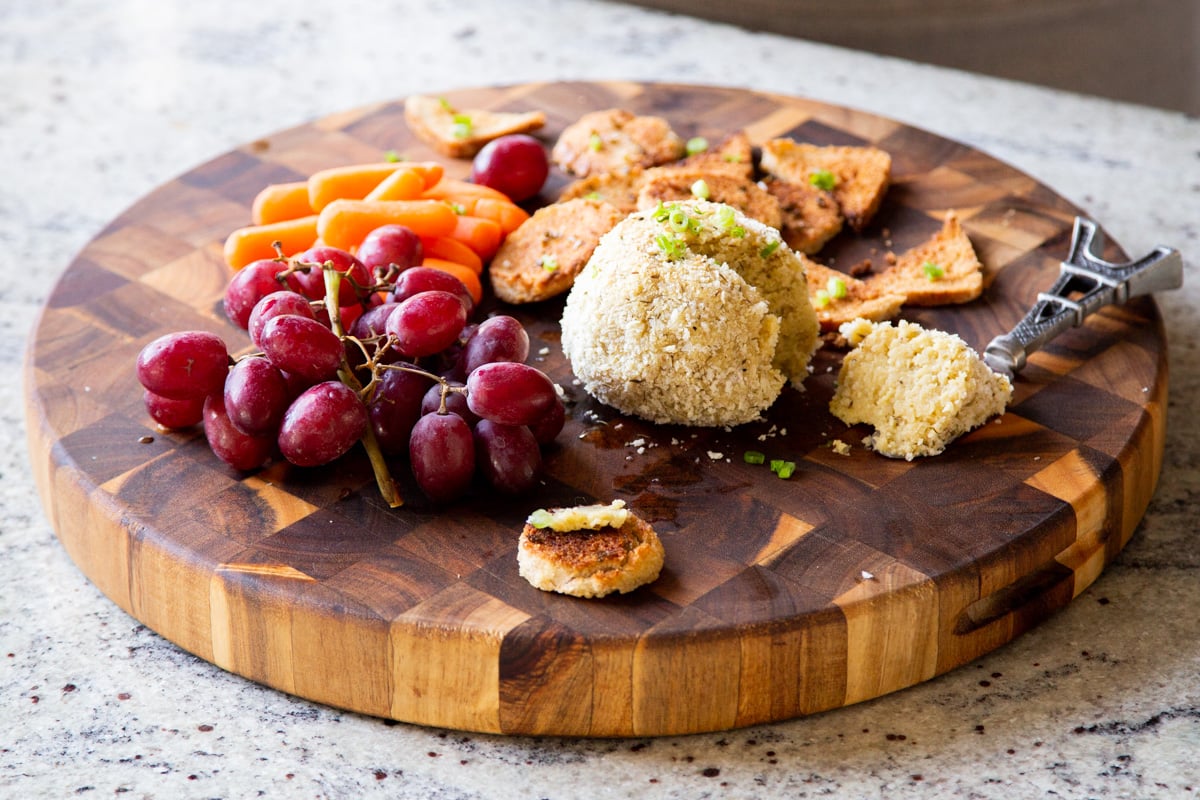 a vegan charcuterie board with crackers, grapes, carrots and a vegan almond flour cheeseball 
