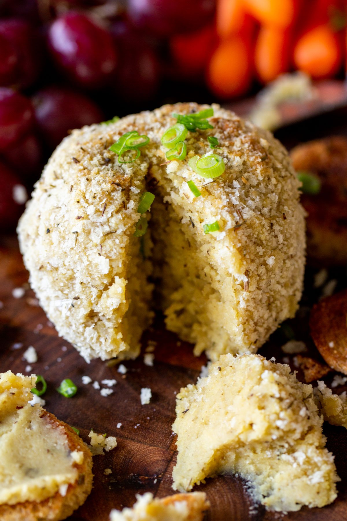 a vegan homemade cheese ball with stuffing seasoned coating placed on a chopping board 