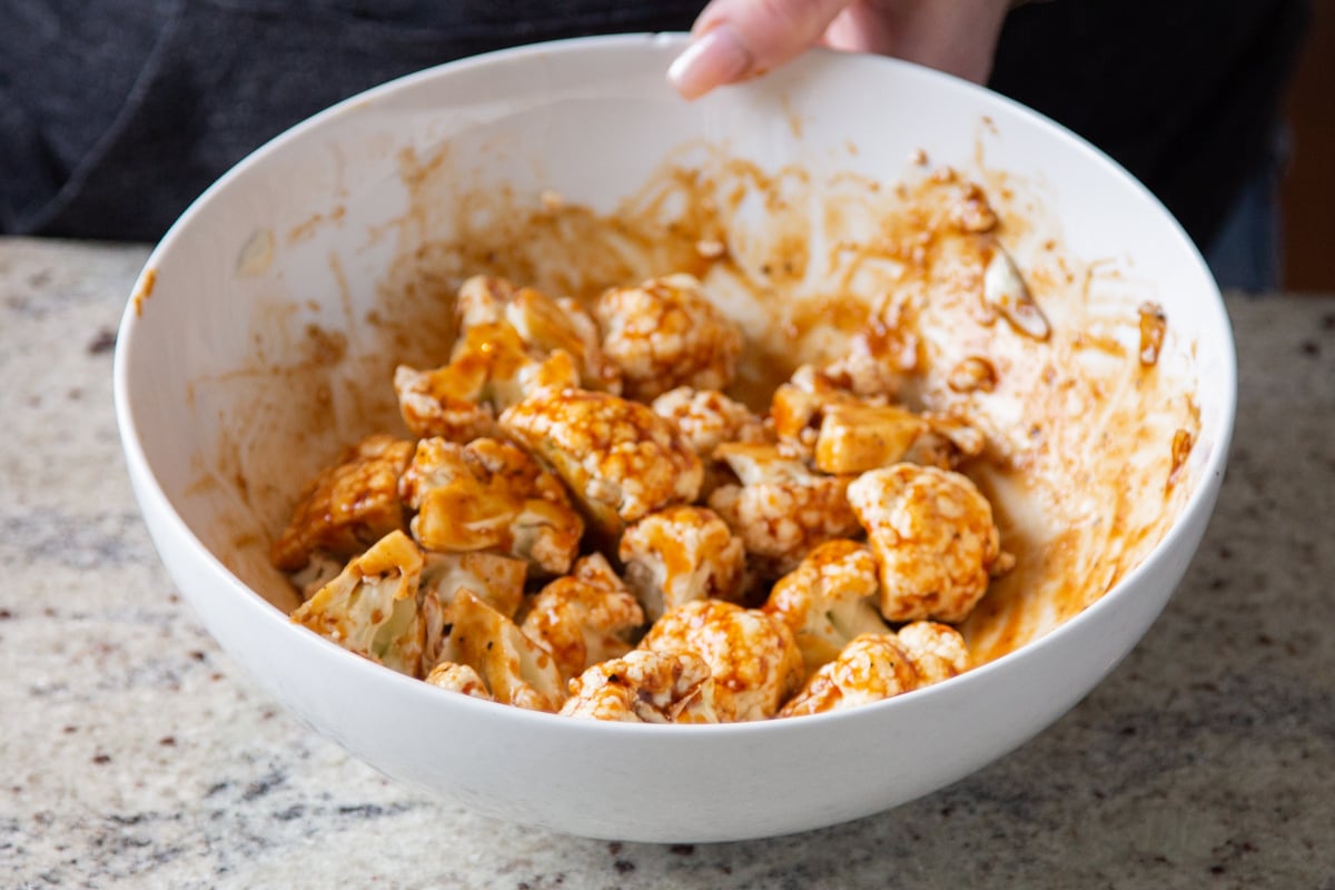 cauliflower florets tossed with spicy sauce in a white bowl