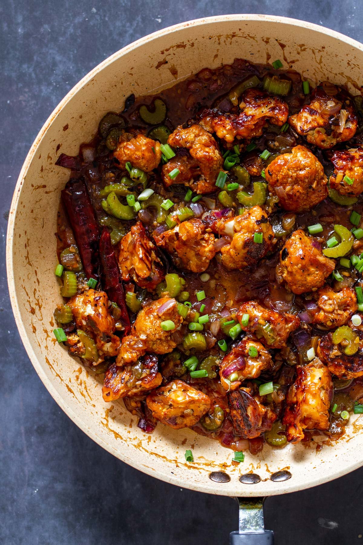 overhead shot of a saucepan with black pepper cauliflower tossed with sweet spicy sauce