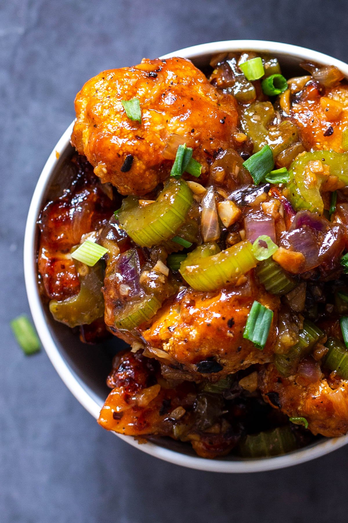 vegan baked cauliflower and celery tossed with spicy sweet sauce in a white bowl
