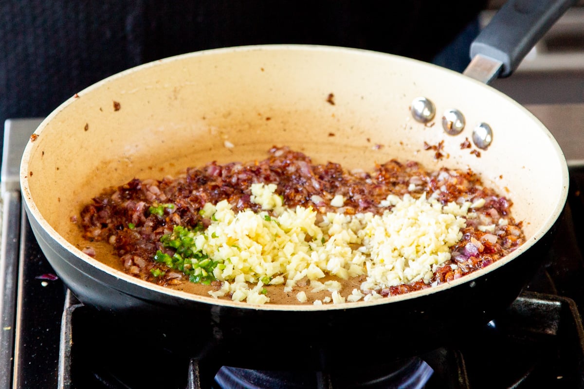minced ginger and green chili along with caramelized onions sauteeing in a frying pan
