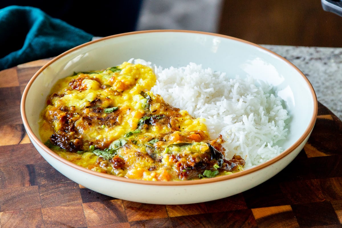 dal served next to white rice in a shallow bowl