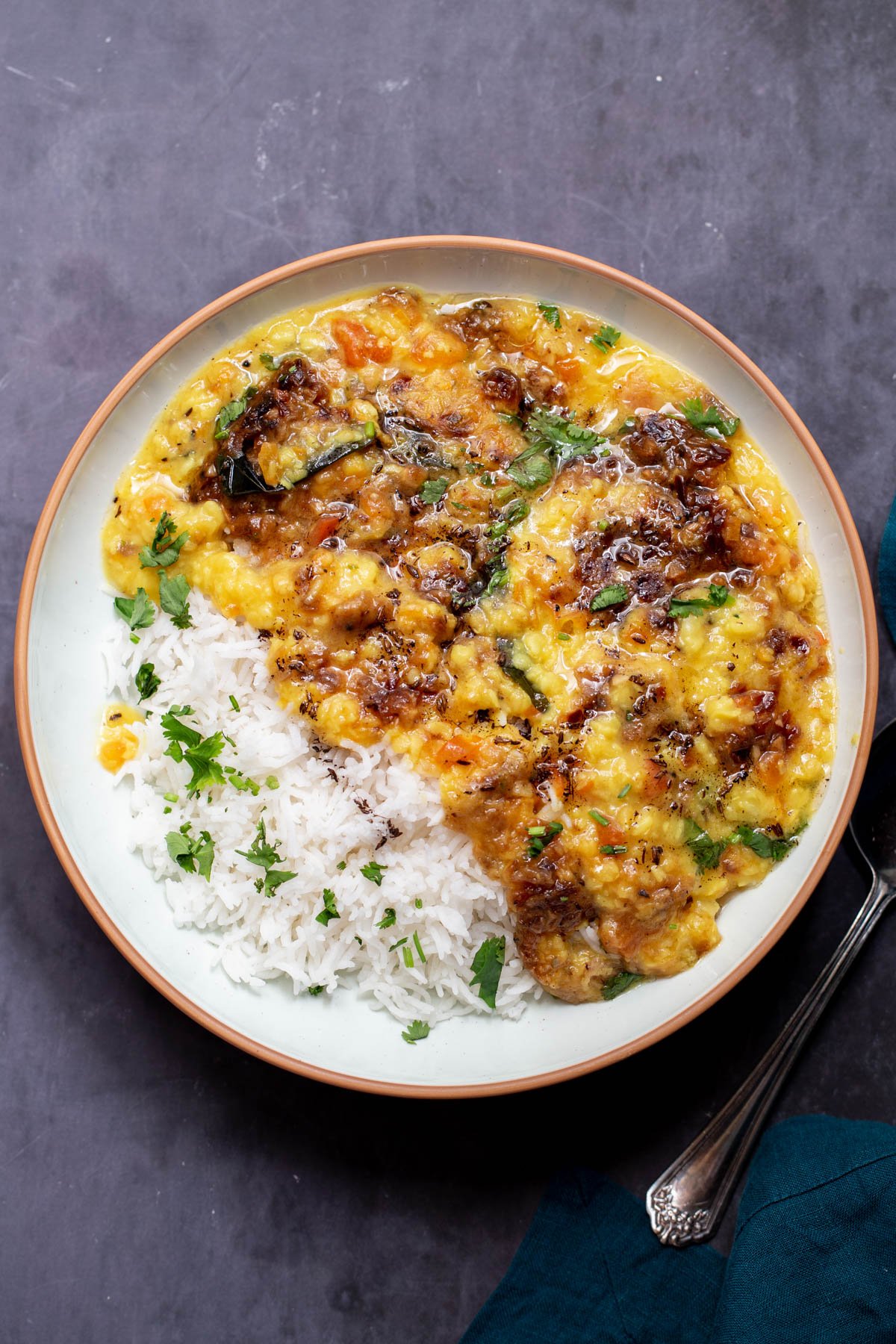a bowl with caramelized onion dal served alongside a side of rice and sprinkled with freshly chopped cilantro