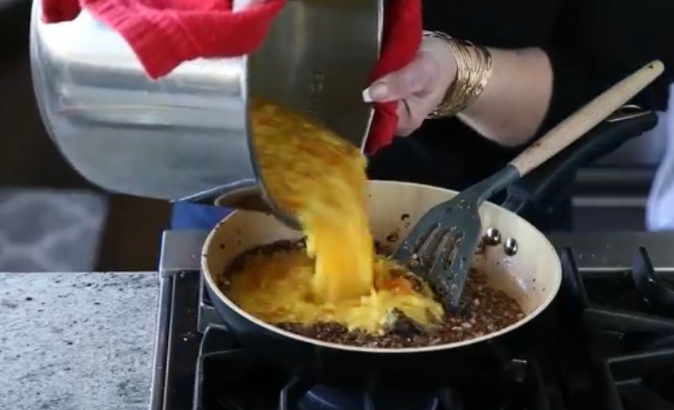 cooked lentils being poured into caramelized onion tadka