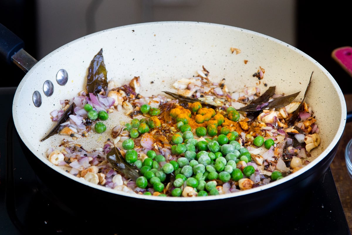 peas, spices and onion in a frying pan