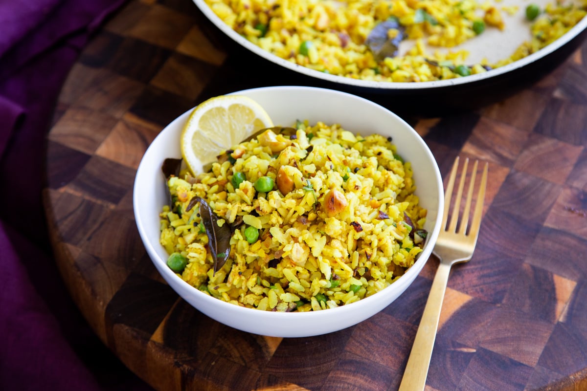 kanda poha served in a small white bowl with a slice of lemon