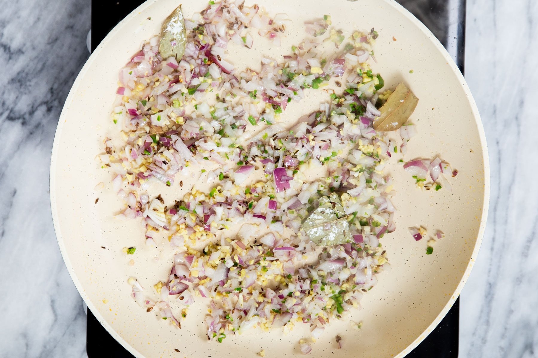 diced onions and ginger sauteeing in a pan with spices 