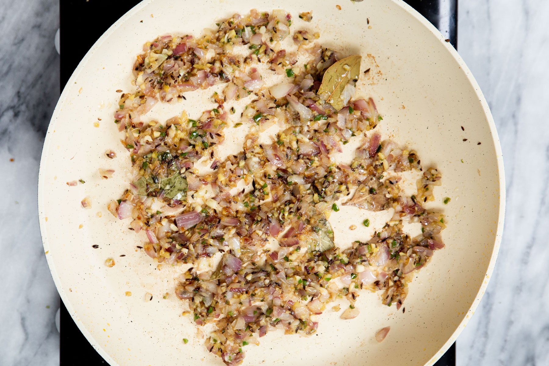 onion, spices and ginger frying in a sauteeing pan