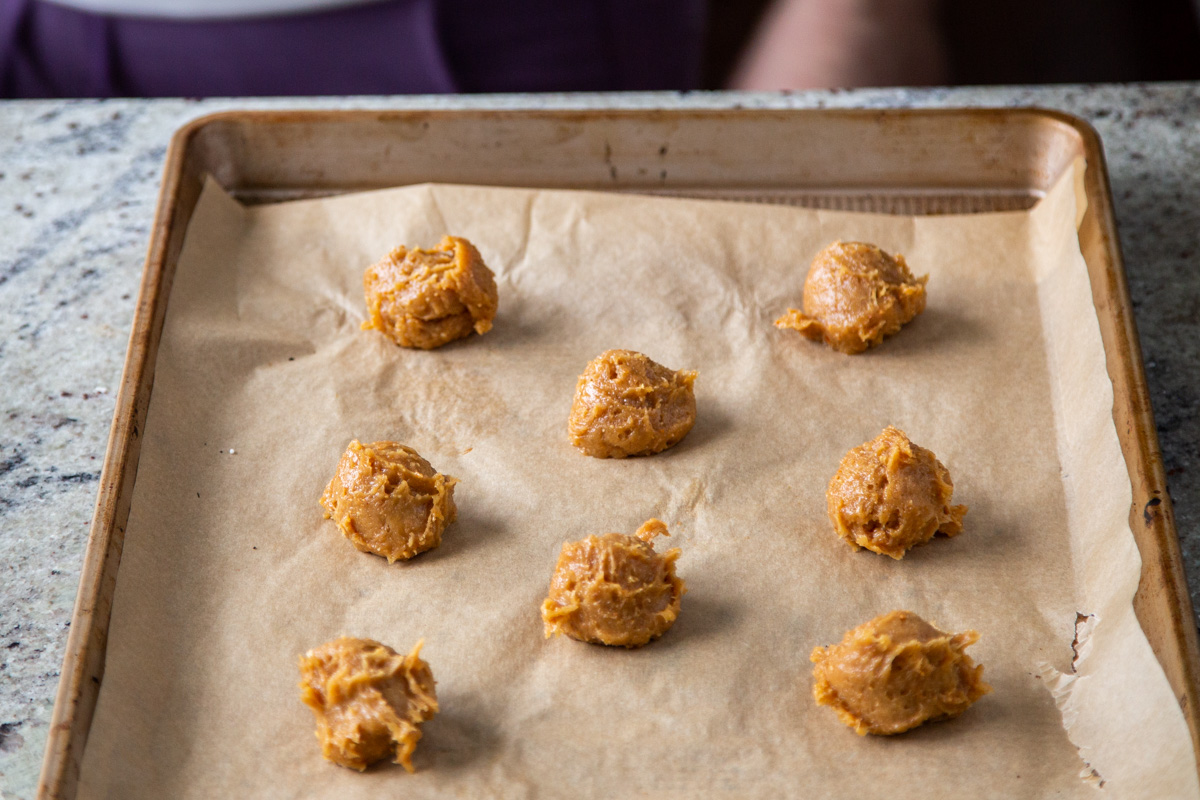 vegan peanut butter batter being scooped onto a baking sheet