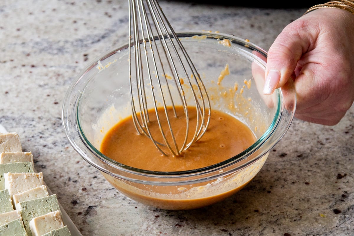 peanut sauce in a glass bowl with a metal whisk