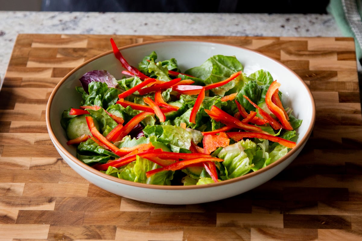greens and sliced bell peppers in a shallow bowl