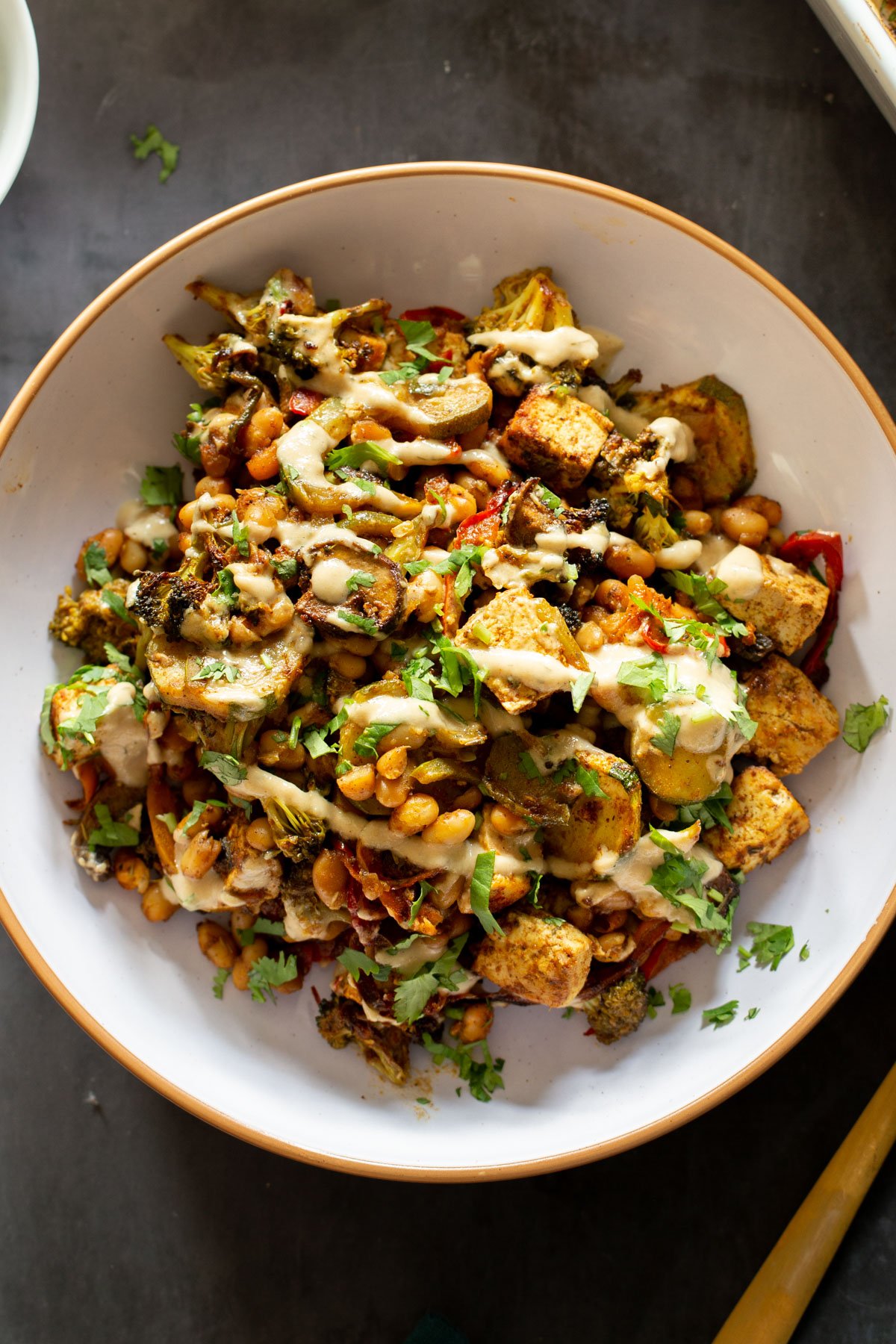 a bowl of baked veggies and tofu seasoned with berbere and drizzled with creamy tahini sauce