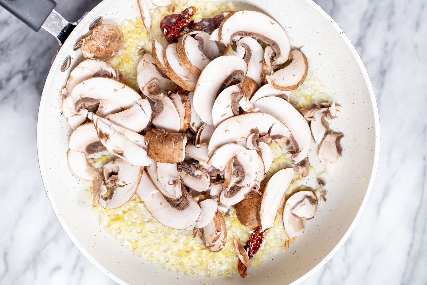 sliced mushrooms, minced ginger and chilies in a frying pan