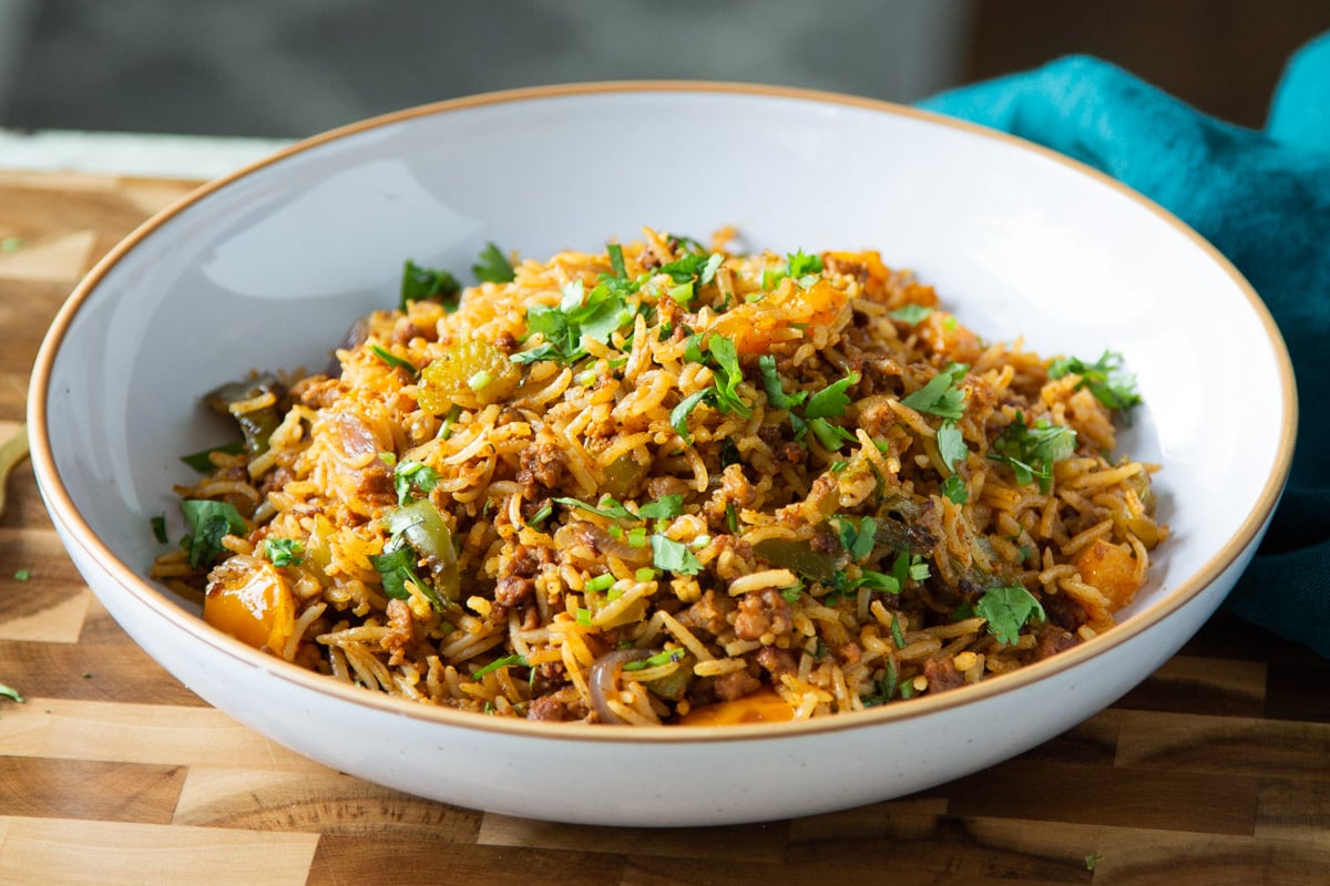 side view of a plate with vegan dirty Cajun rice topped with chopped cilantro leaves