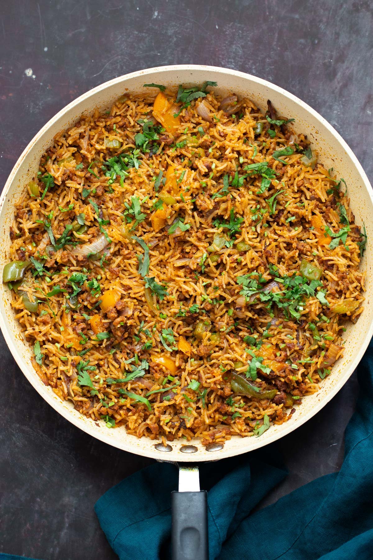 a frying pan with Cajun dirty rice topped with chopped cilantro