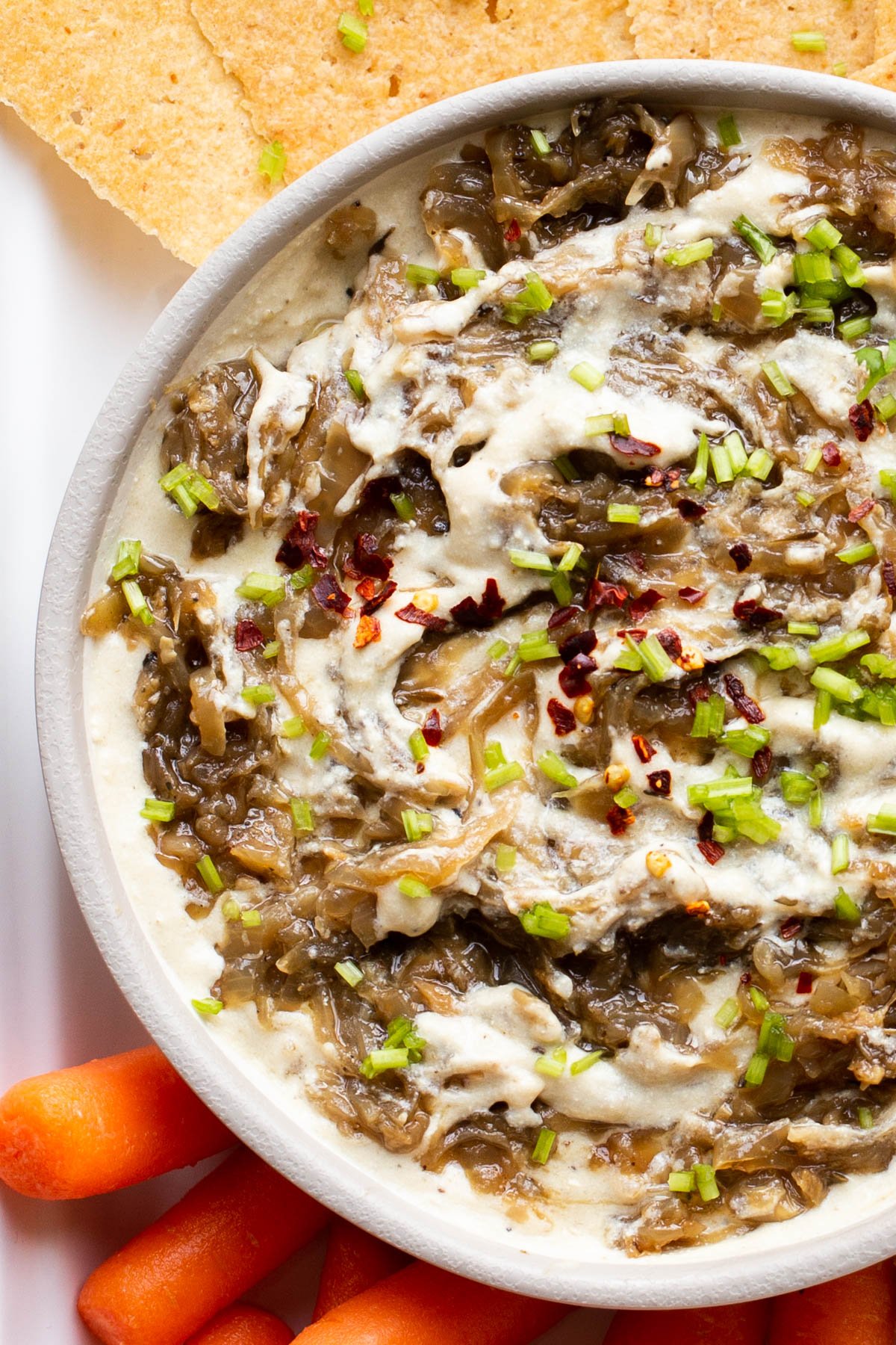 overhead close-up of caramelized French Onion Dip surrounded with crackers and veggies