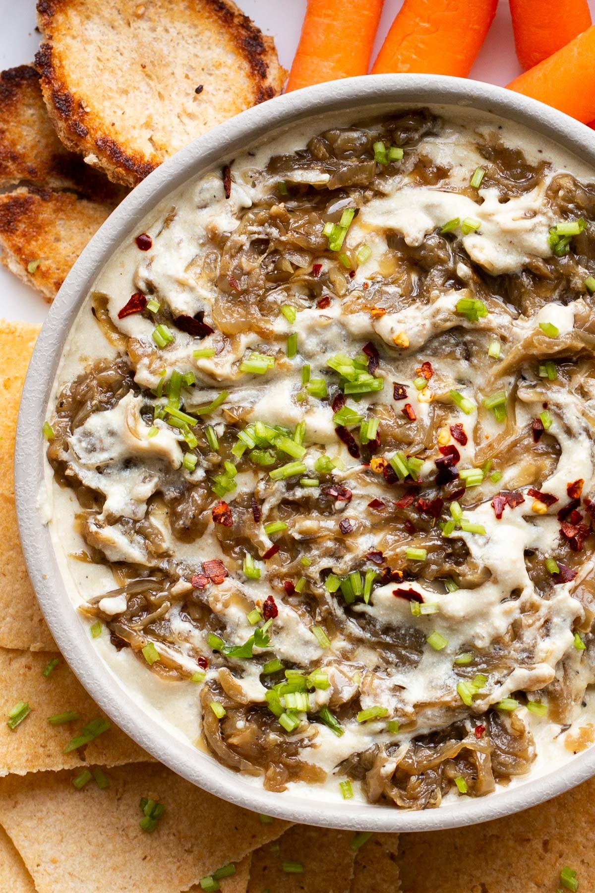 a bowl with vegan French Onion Dip served surrounded with vegetables and crackers