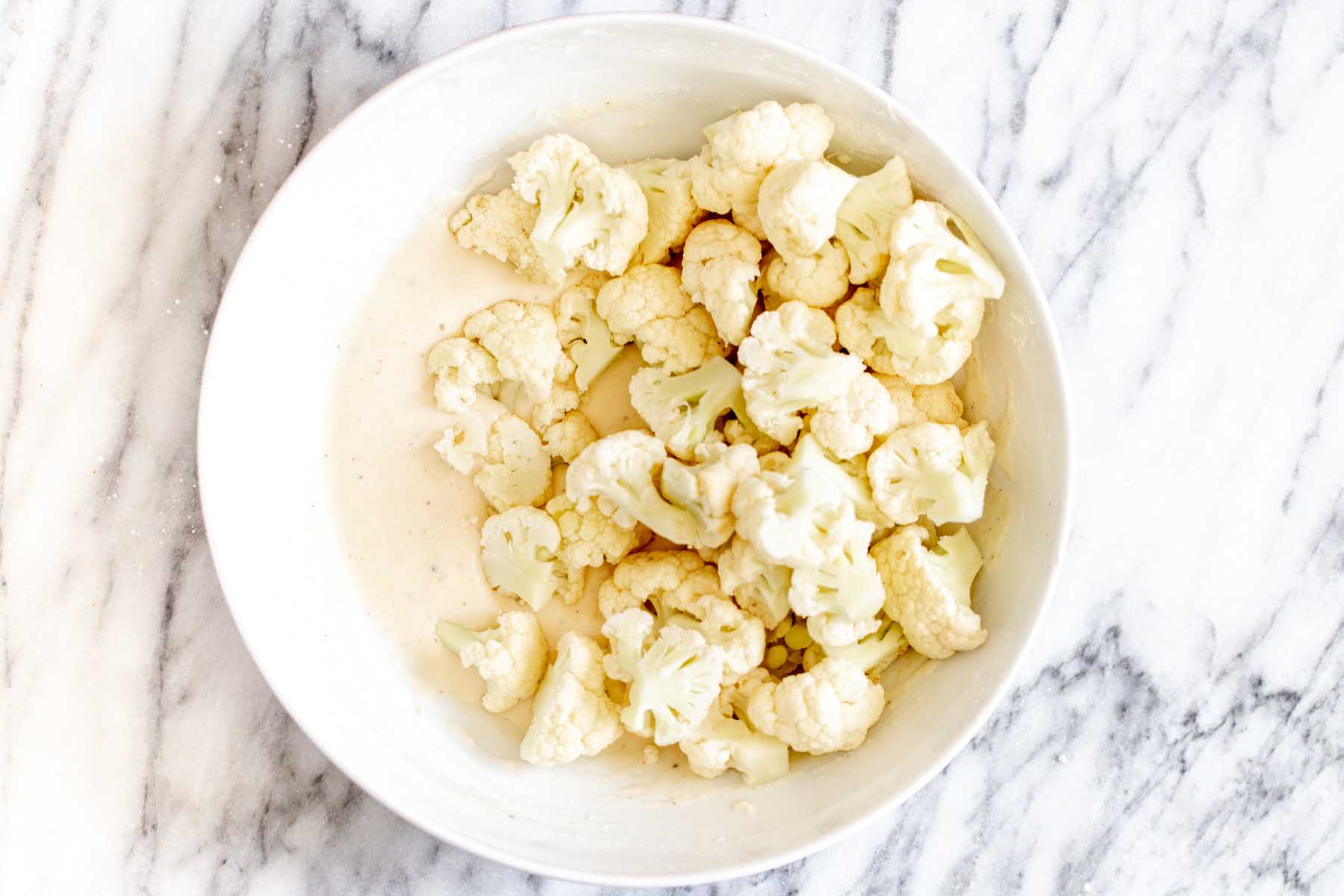 cauliflower in the bowl with the batter before tossing together