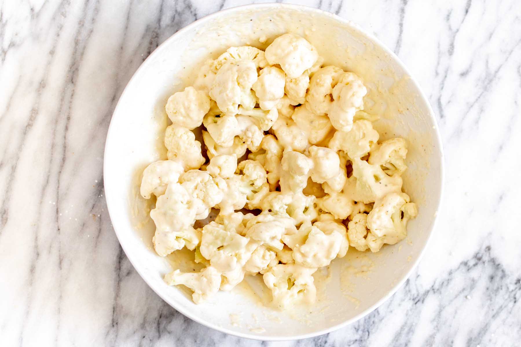 cauliflower in the bowl with the batter after tossing together