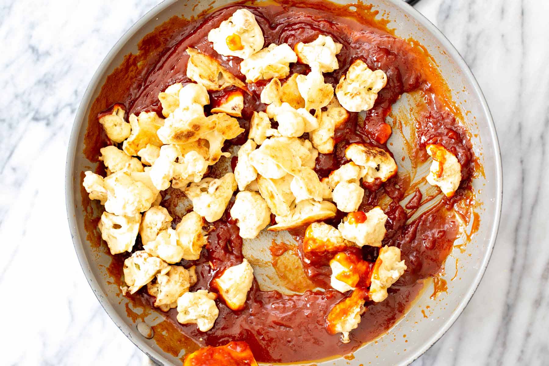adding cauliflower to the pan of gochujang sauce