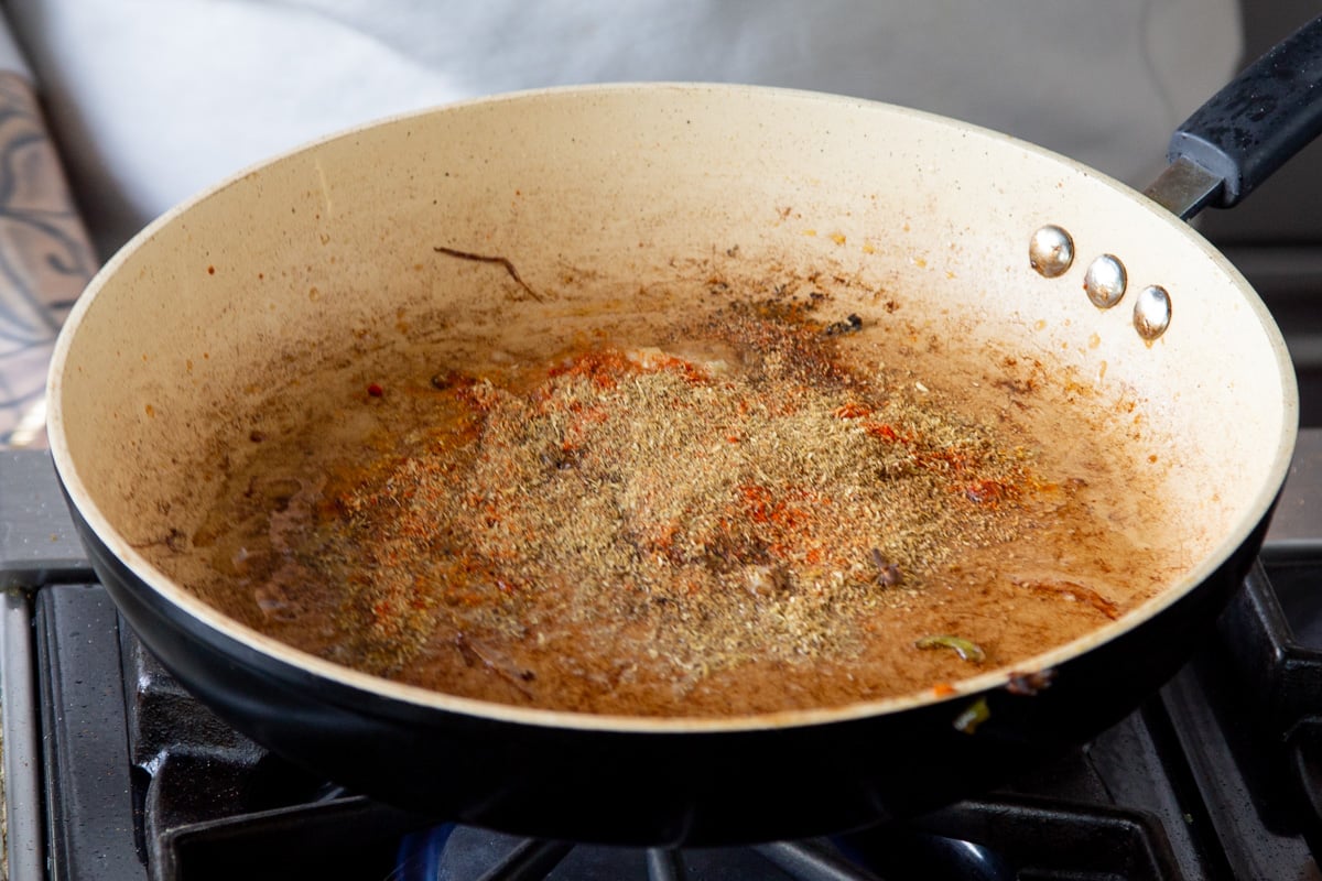 spiced being added to a frying pan