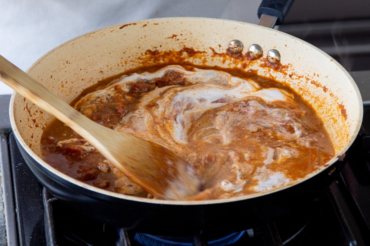 creamy vegan yogurt being stirred into patiala base sauce
