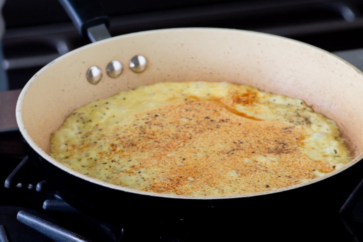 just egg being added to a sauteeing pan to make vegan omelet