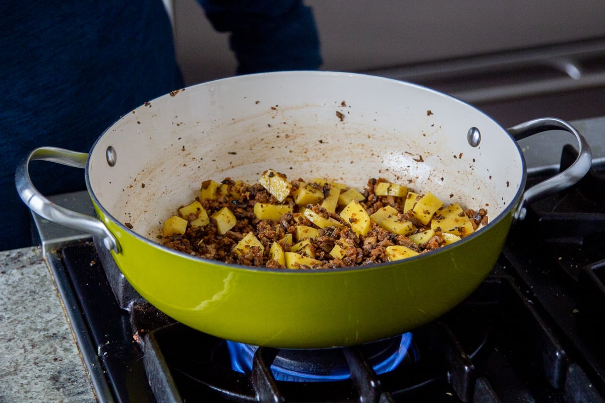 a pan with vegan sausage crumbles and cubed potatoes
