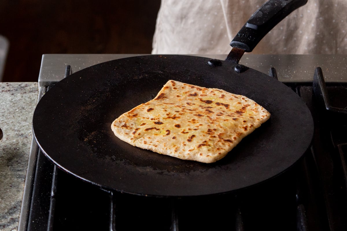 aloo paratha on a skillet after flipping