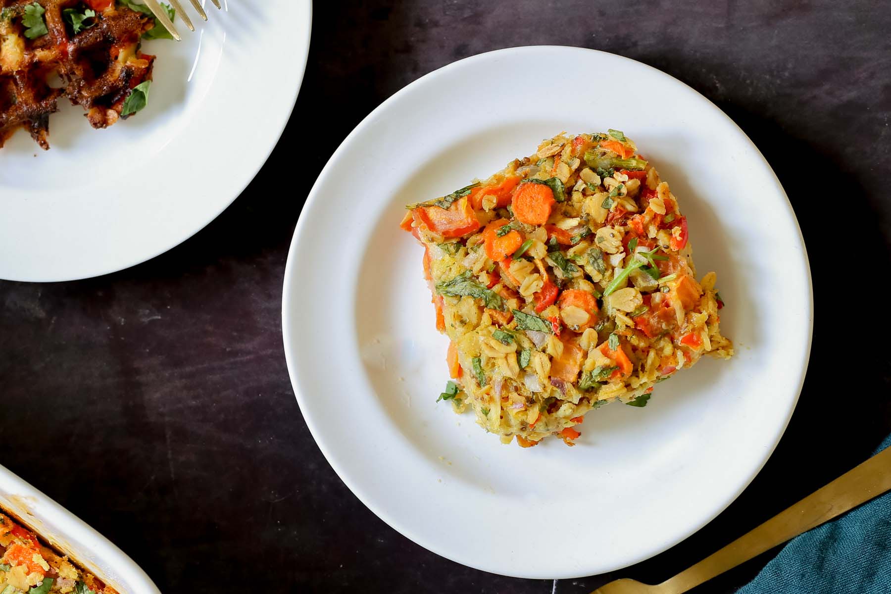 a piece of savory baked oatmeal on a white plate next to other breakfast items