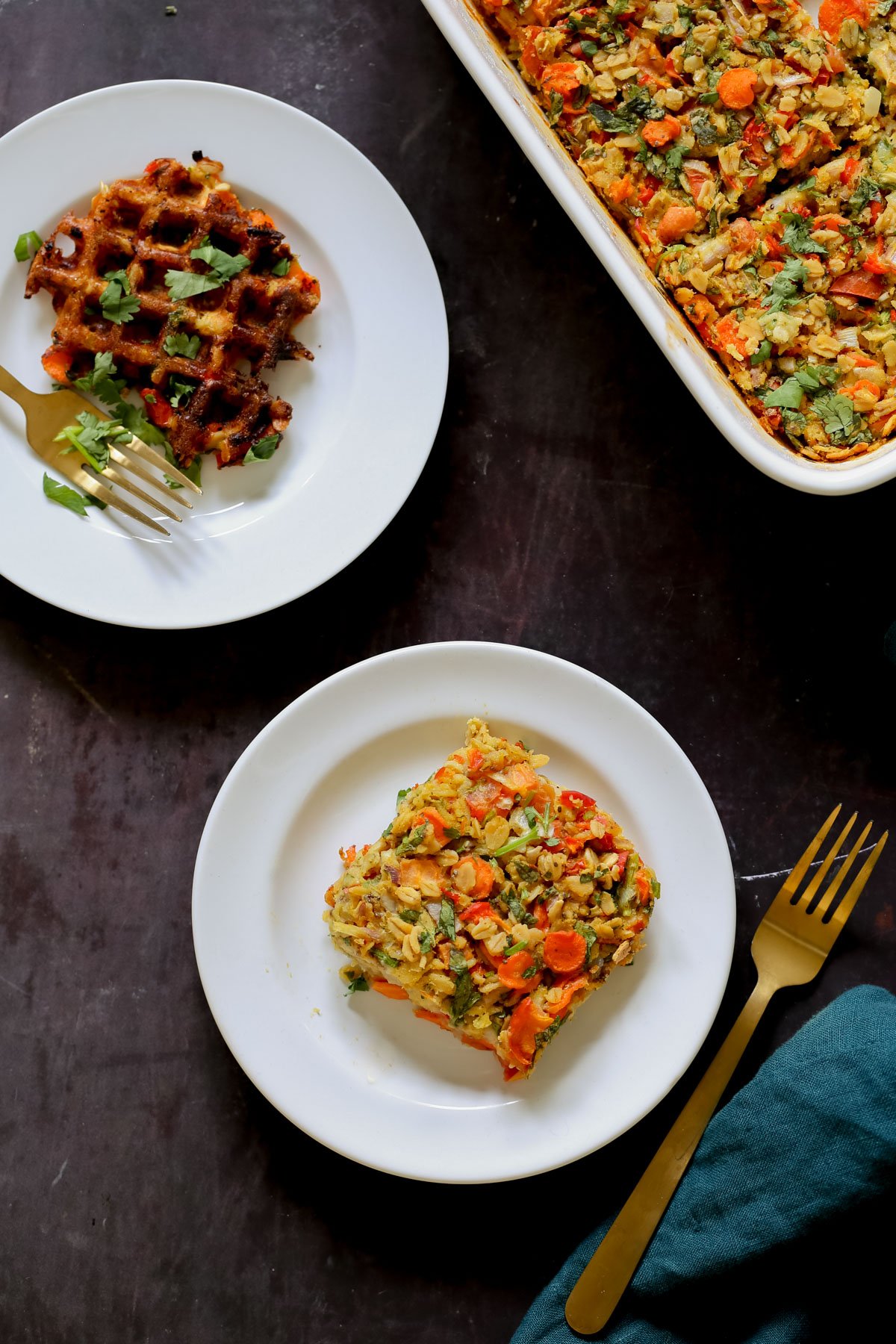 a piece of savory baked oats on a white plate next to the baking pan and a waffle