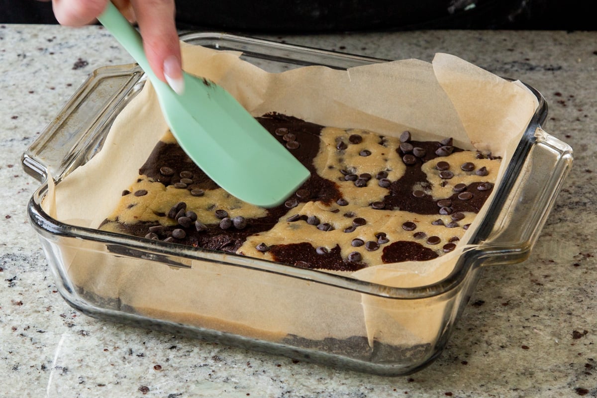 flattening the brookie doughs with a spatula