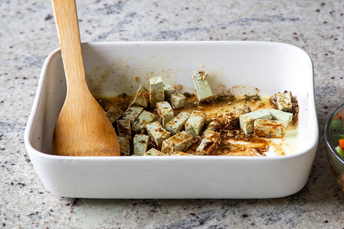 adding tofu to the spices in the pan