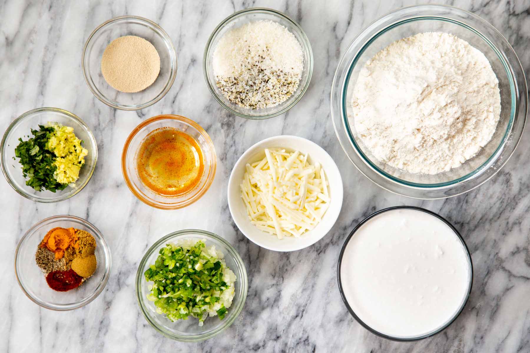 flour, vegan cheese, and other Ingredients in bowls on a marble table