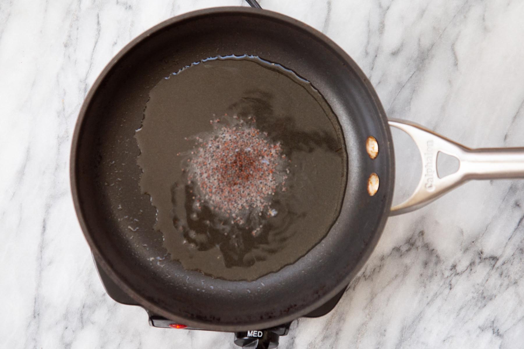 frying mustard seeds for the tempering in a black pan