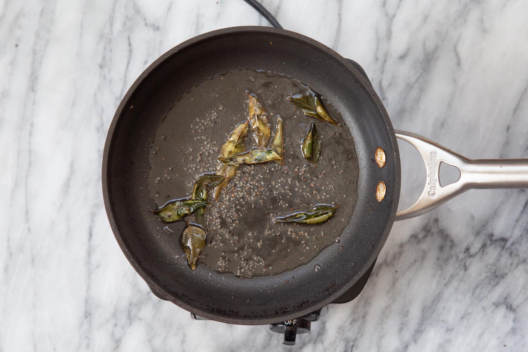 pan of mustard seeds with curry leaves added