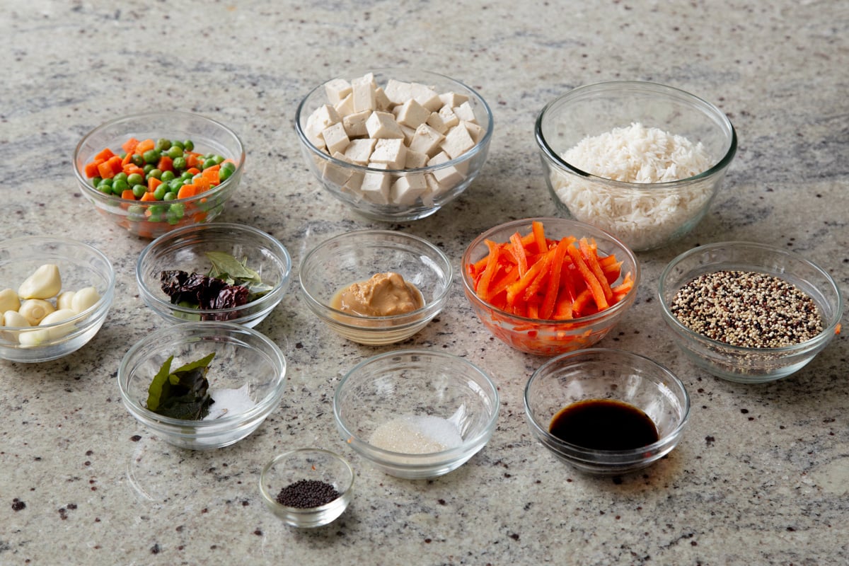 tofu, rice, veggies, and spices in bowls on a kitchen counter