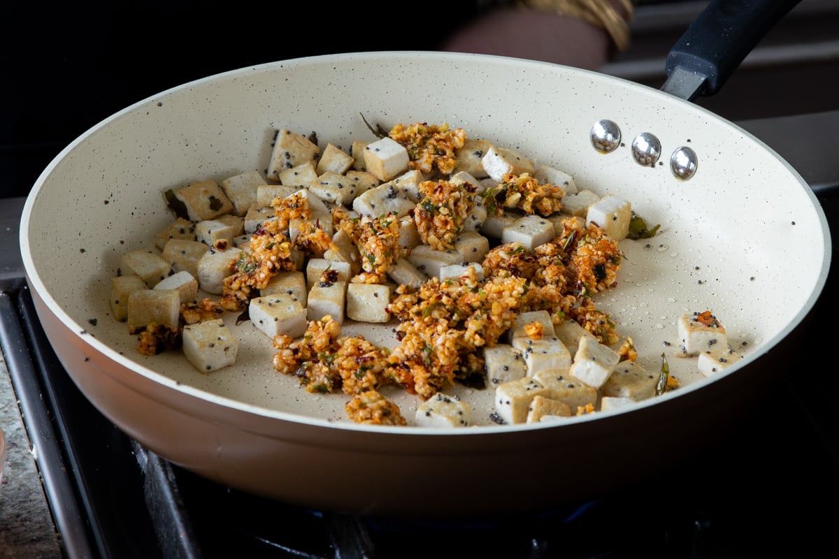 adding podi chutney to the pan with the tofu