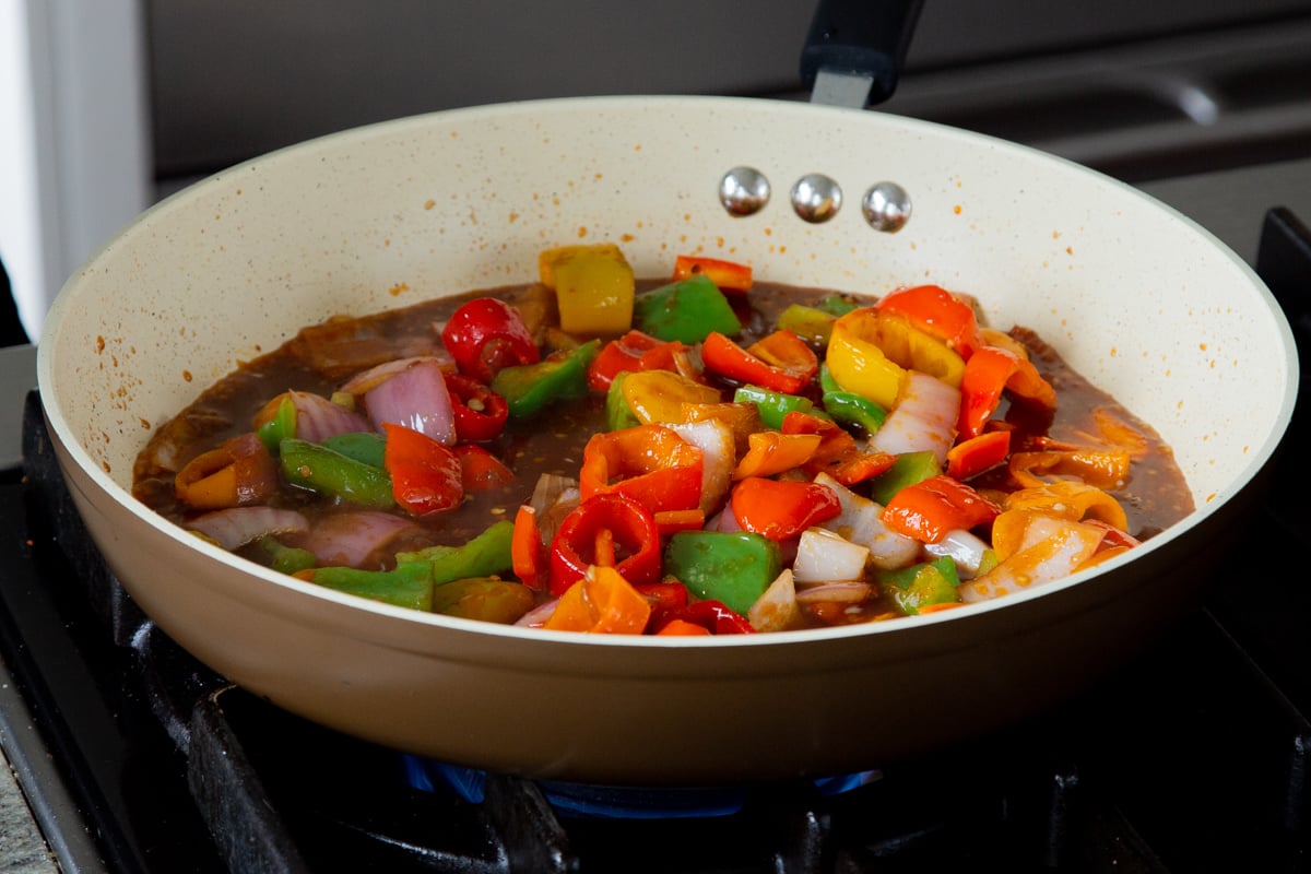 peppers and onions in the frying pan with gochujang and other sauces added, after mixing