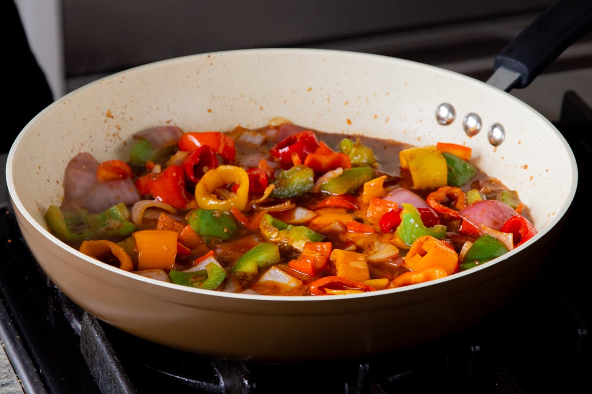 peppers and onions in the frying pan with gochujang and other sauces added, after cooking