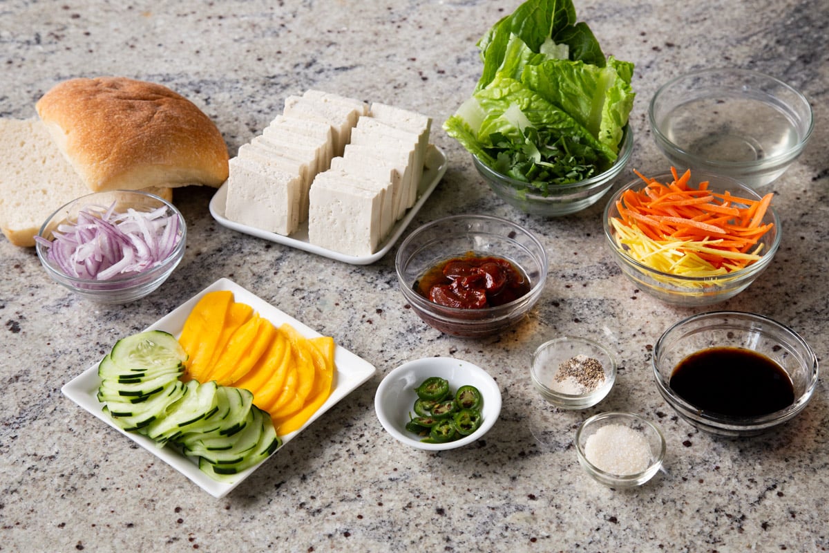 tofu, veggies, gochujang, and other sandwich ingredients on a marble table