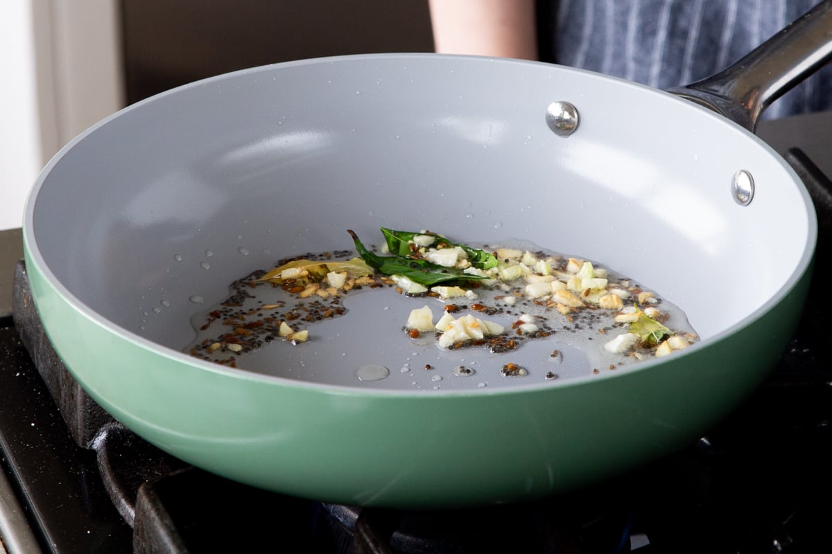 adding garlic and spices to the tempering in the pan