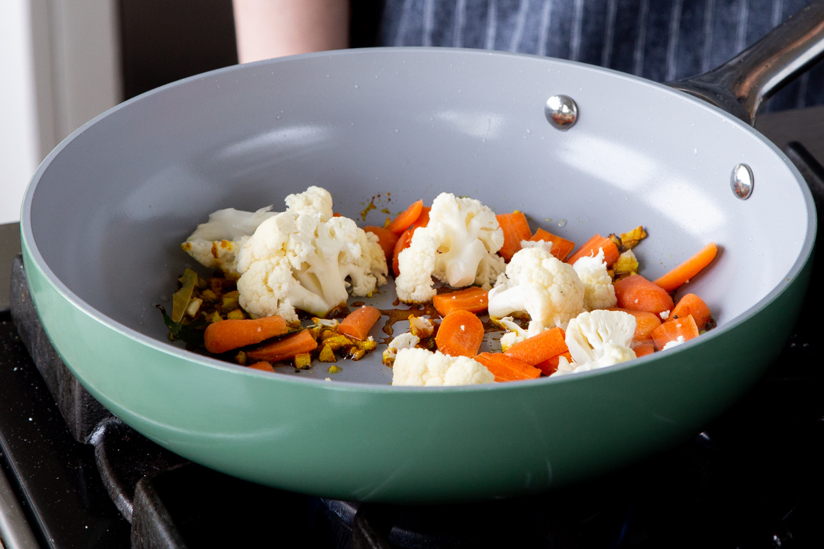 cauliflower and carrots in a baking pan with the tempering, before cooking