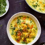 bowl of vegan kadhi pasta with veggies next to the pan and a dish of cilantro