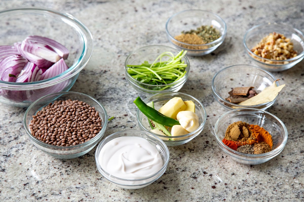 lentils, spices, aromatics, and non-dairy yogurt in bowls on a kitchen counter