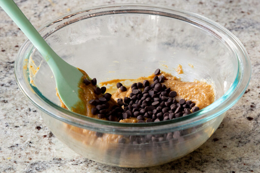 adding chocolate chips to the cookie dough batter